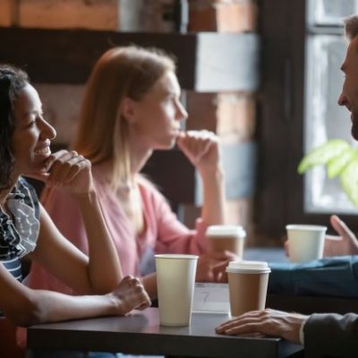 A woman sitting across from a man at a table, the man looks as though he is laughing while the woman is smiling